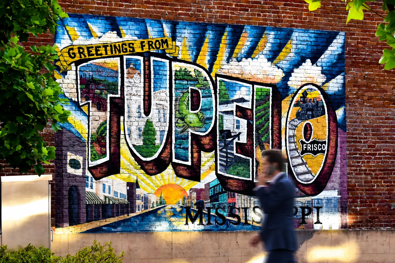 Tupelo attorney walking through downtown Tupelo, Mississippi Attorney in a suit walking past the Greetings from Tupelo mural in downtown Tupelo, Mississippi